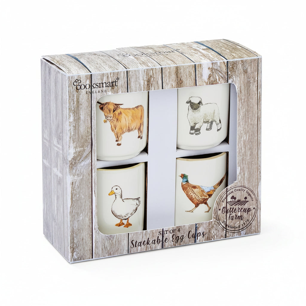 A boxed set of four stackable egg cups with illustrated farm animals: a brown cow, a white sheep, a white duck, and a pheasant. The product is shown in its rustic wood-textured gift box with Cooksmart branding and a Buttercup Farm logo.