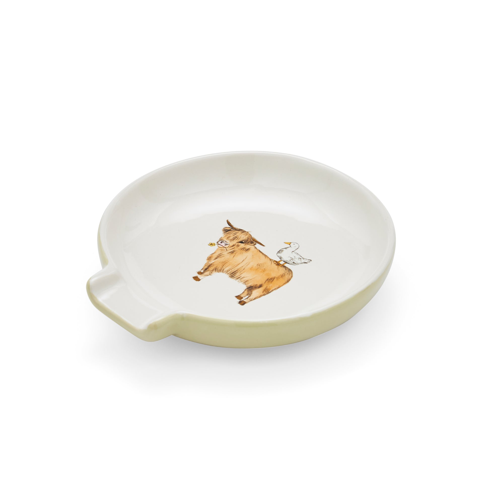 A round off-white ceramic dish with a small handle on the left side, featuring a hand-painted illustration of a brown cow and a white bird in the center, set against a plain white background.