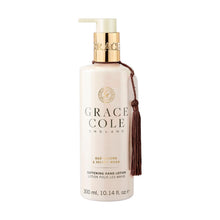 Grace Cole Oud Accord & Amber Hand Lotion 300ml in a clear pump bottle with a gold dispenser and decorative tassel, enriched with shea butter to moisturise dry hands.