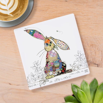 Cartco Bug Art Binky Bunny square ceramic coaster with a colourful patterned rabbit illustration on a wooden table.