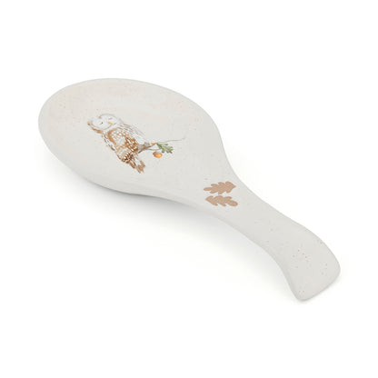 Cartco ceramic spoon rest in cream with a speckled finish, featuring an owl illustration and oak leaf handle details.
