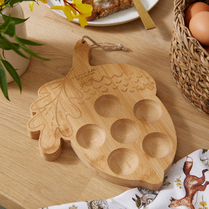 Cartco Cooksmart Forest Fable bamboo egg holder shaped like an acorn with six circular indentations on a wooden table