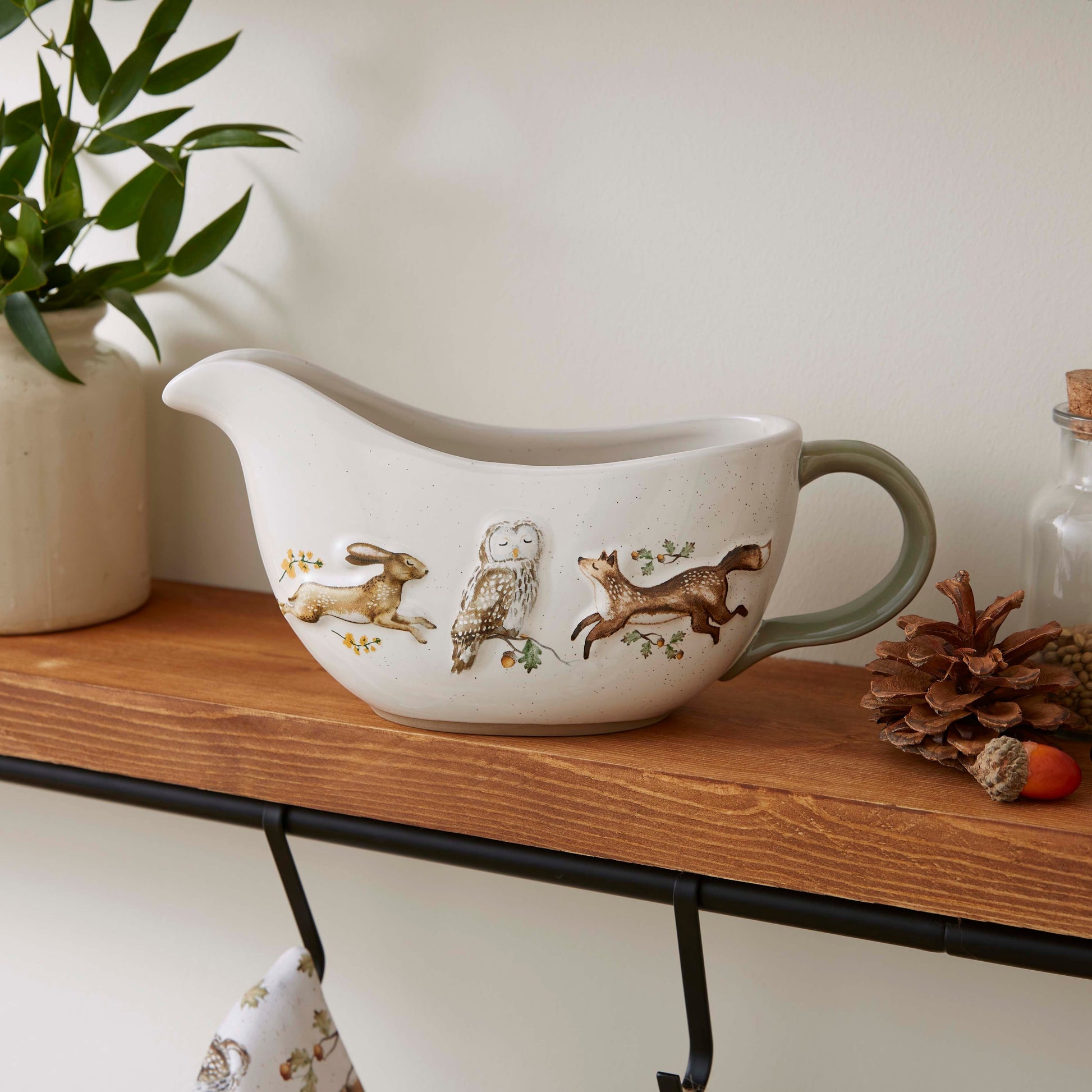Cartco Cooksmart Forest Fable ceramic gravy boat with woodland hare, owl, and fox illustrations and sage green handle.
