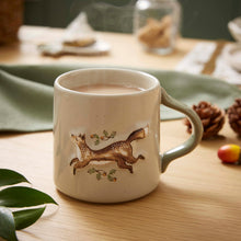 Cartco Cooksmart ceramic mug with a running fox, oak leaves, and acorns on a speckled cream body with a sage handle.