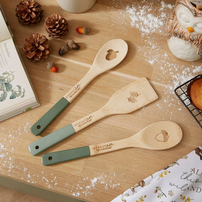 Cartco Forest Fable bamboo utensil set featuring sage green handles and woodland animal engravings on a wooden table