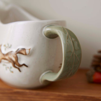 Cartco Cooksmart Forest Fable ceramic gravy boat featuring a sage green handle and woodland animal illustrations.