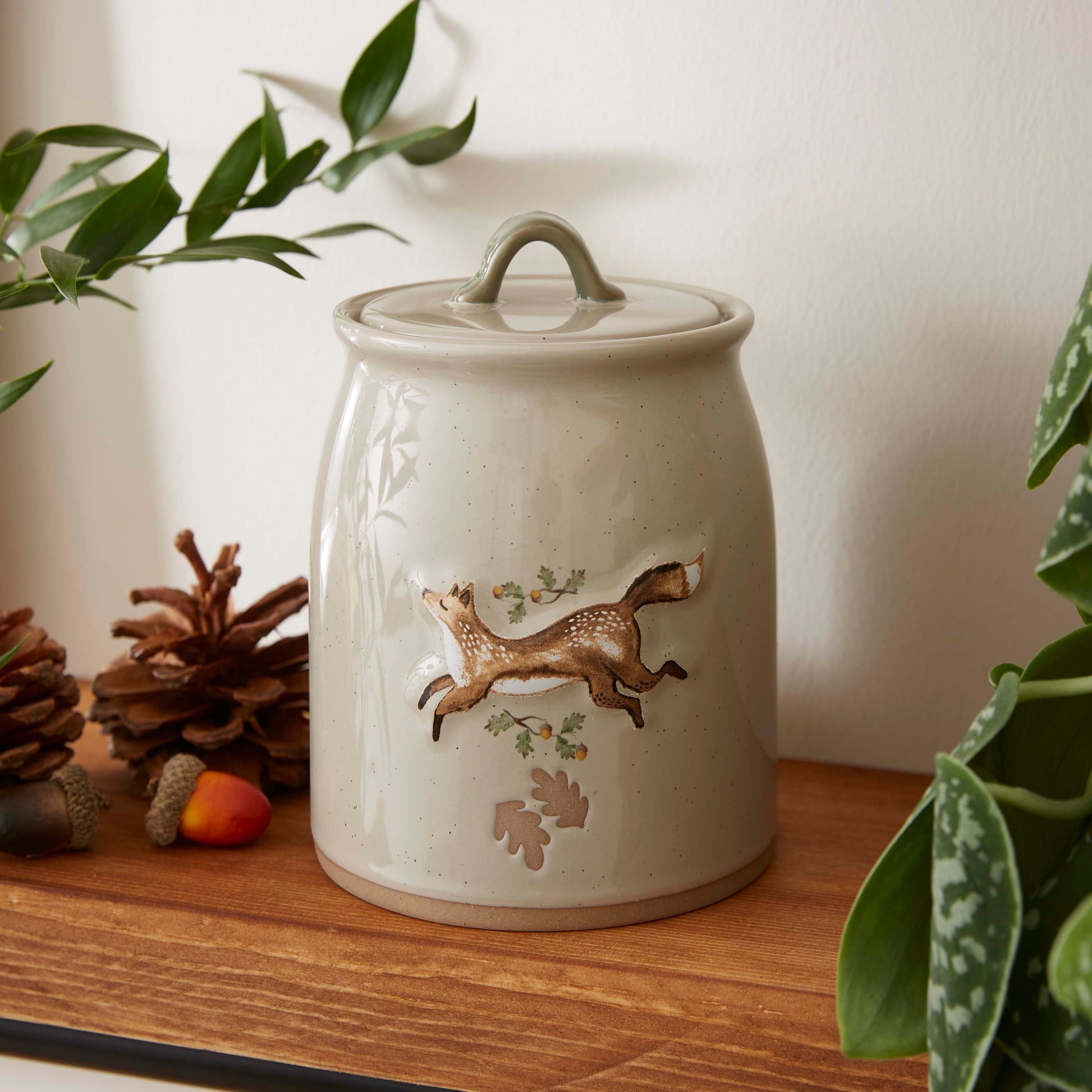 Cartco Cooksmart Forest Fable ceramic canister in cream with a running fox, oak leaf, and acorn design and loop lid.