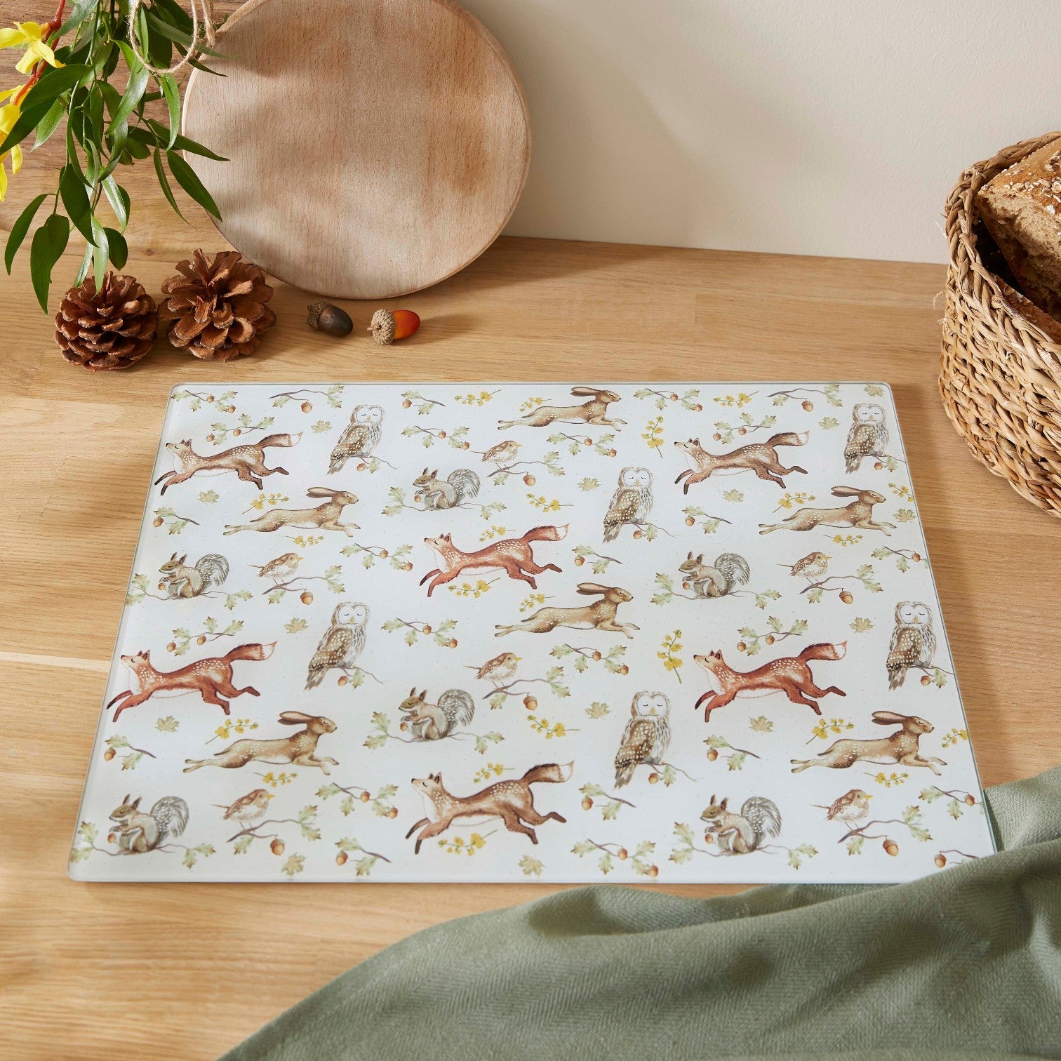 Cartco Cooksmart Forest Fable glass worktop saver with woodland fox, owl, and hare illustrations on a kitchen counter.