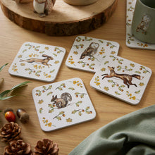 Cartco Cooksmart Forest Fable square coasters featuring hare, owl, fox, and squirrel illustrations on a wooden table.