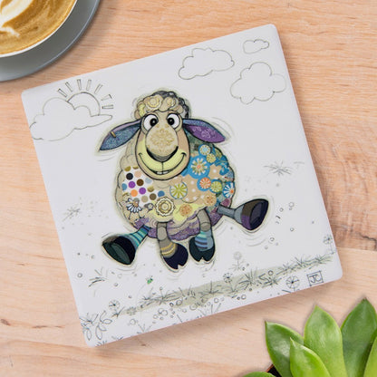 Cartco Bug Art Sasha Sheep ceramic coaster with a whimsical sheep illustration on a wooden table surface.